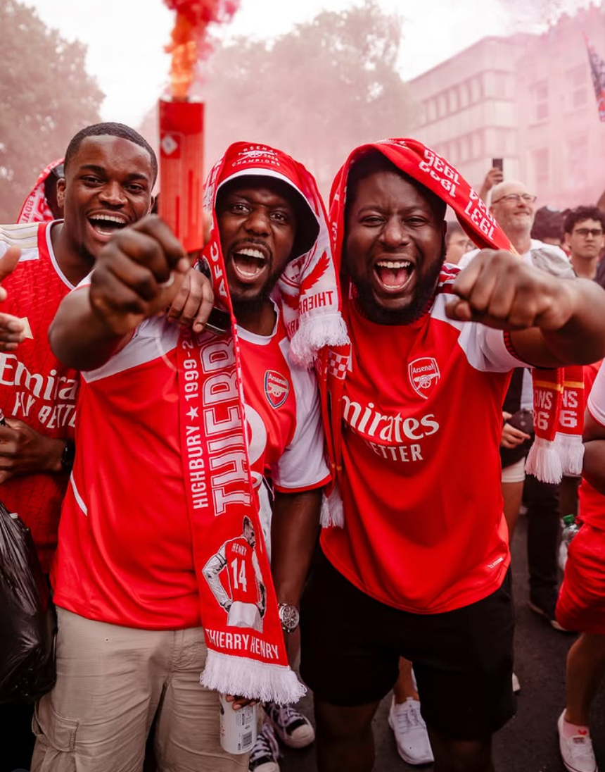 Arsenal supporters in red smoke pointing at the camera